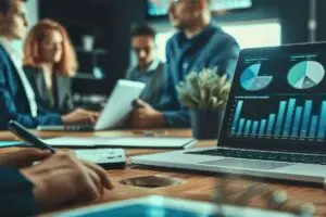 Reunión de equipo analizando gráficos financieros en una laptop, representando la importancia de la planificación estratégica en la implementación de ERP para evitar excesos presupuestarios.