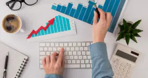 Persona analizando gráficos de crecimiento y rendimiento en un escritorio, representando la importancia de la diferenciación y la estrategia de precios en el sector retail.